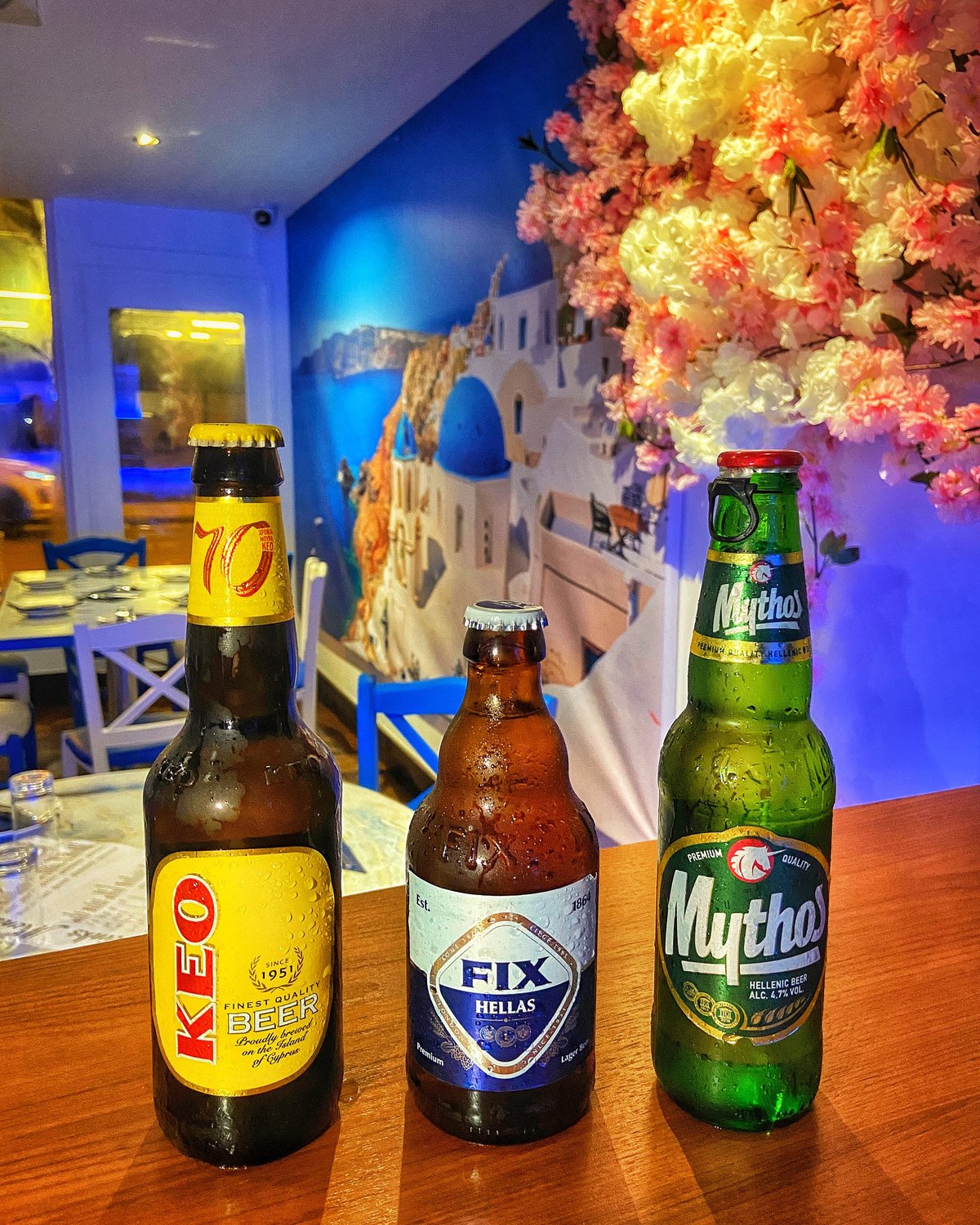 Greek beers at Zorba The Greek — KEO, Fix Hellas and Mythos on the bar, with the restaurant's blue-walled dining room behind