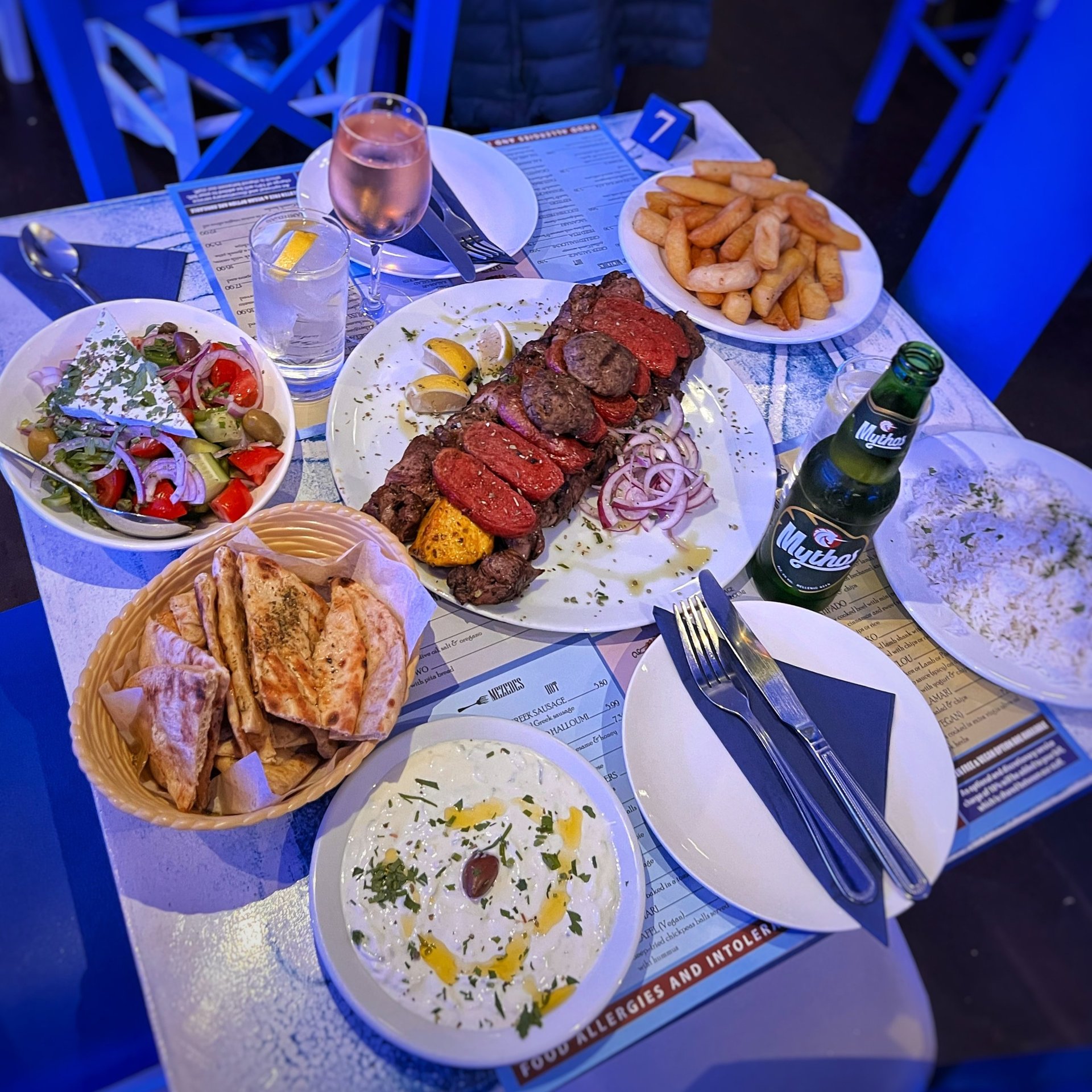 A table crowded with sharing plates of Greek food